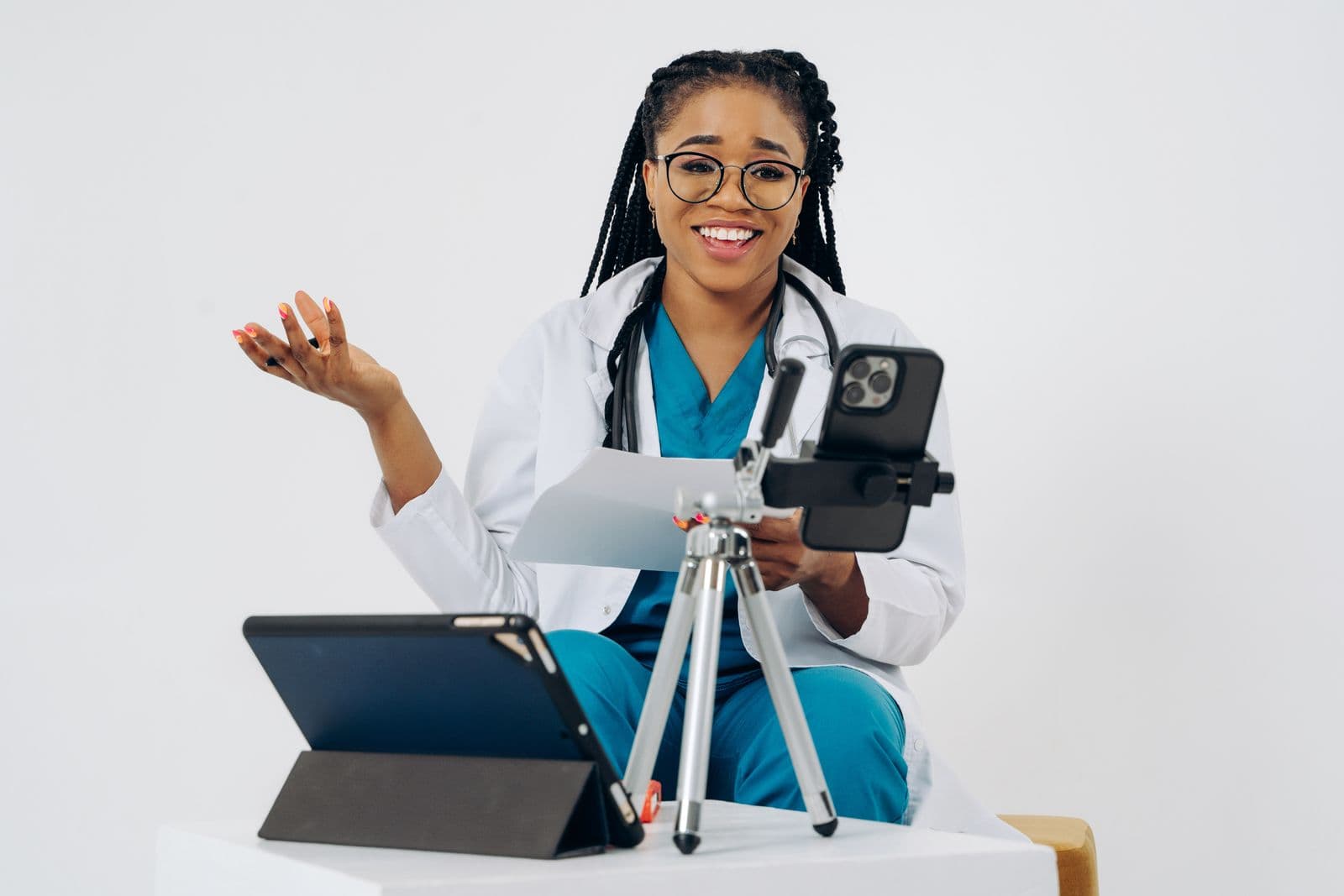 A smiling doctor holding a document during a video consultation