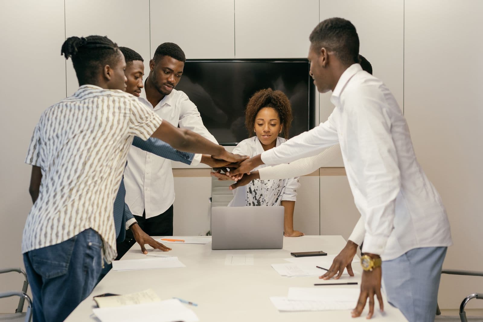 A team stacking their hands together over a desk