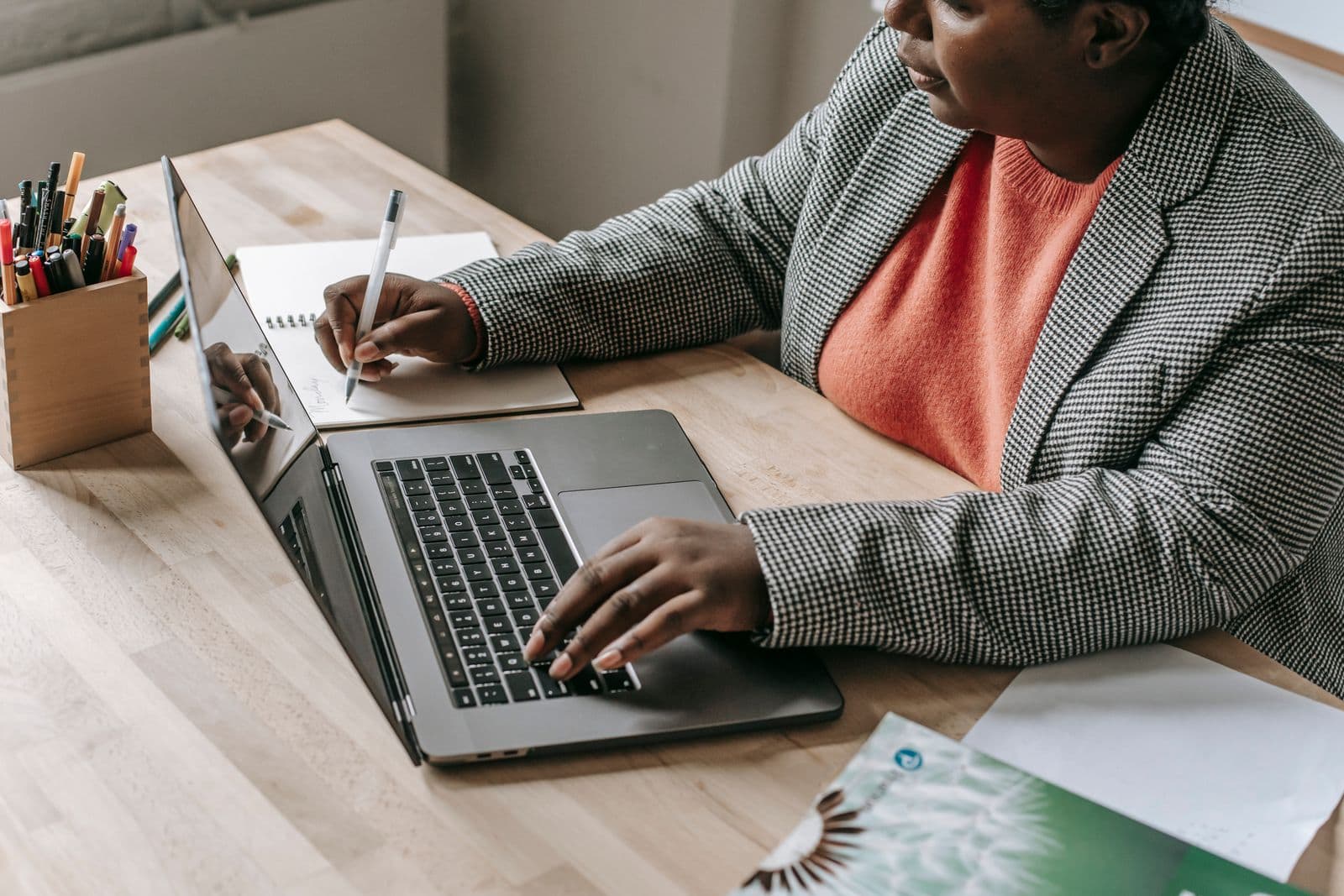 A woman in a blazer working on a laptop at her desk