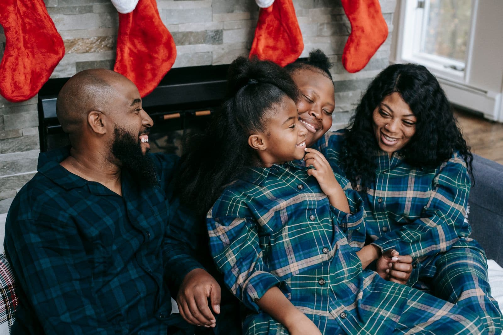 A happy family of four hugging together on a sofa