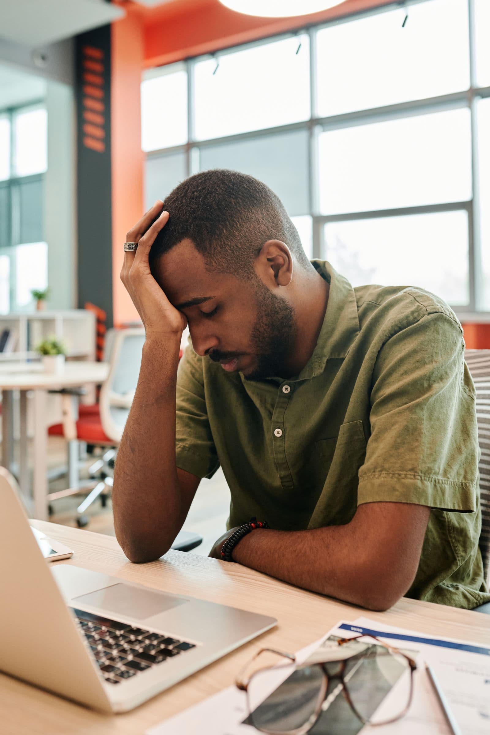 A tired man resting his head on his hand at his office desk