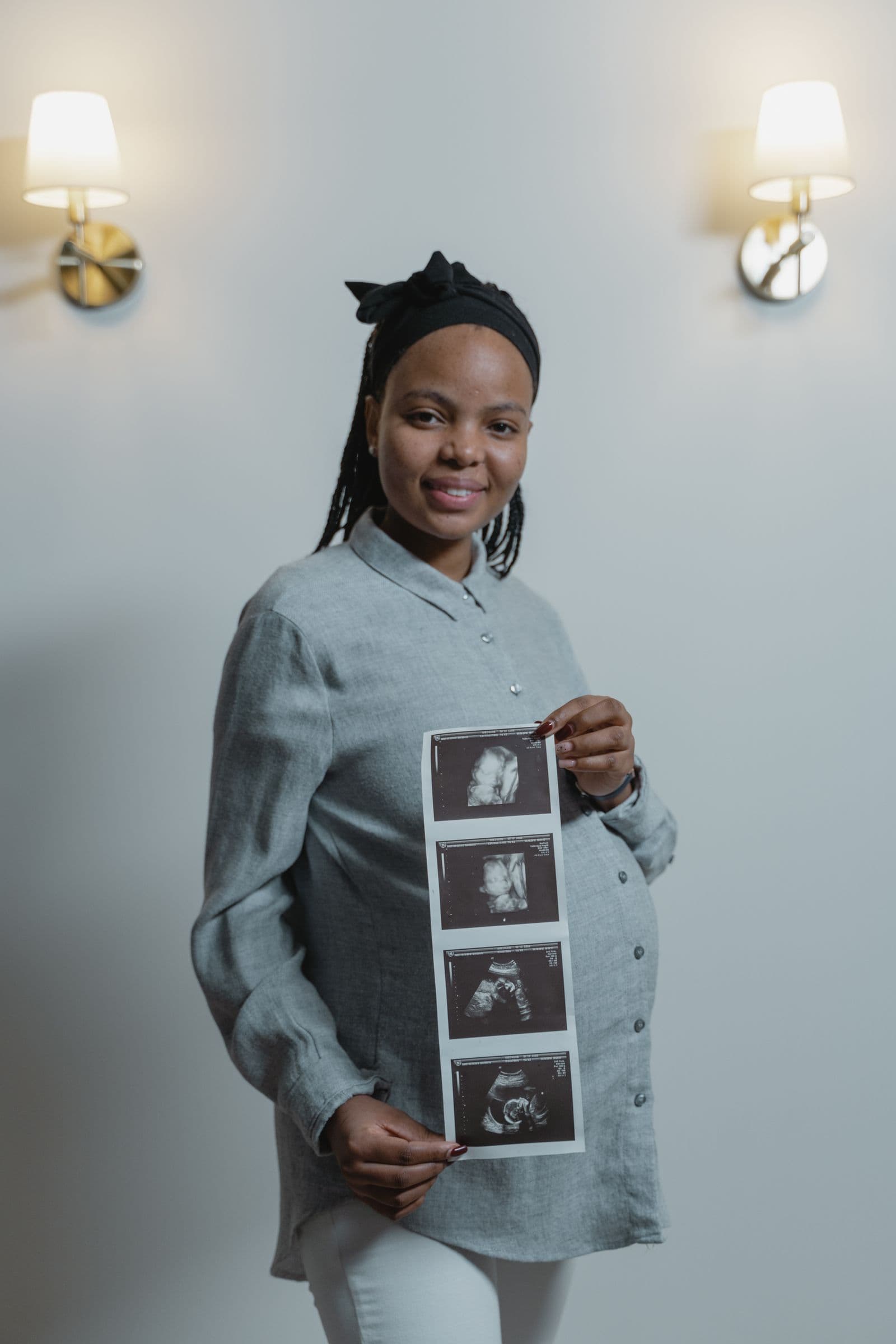 A pregnant woman smiling and holding ultrasound scan photos